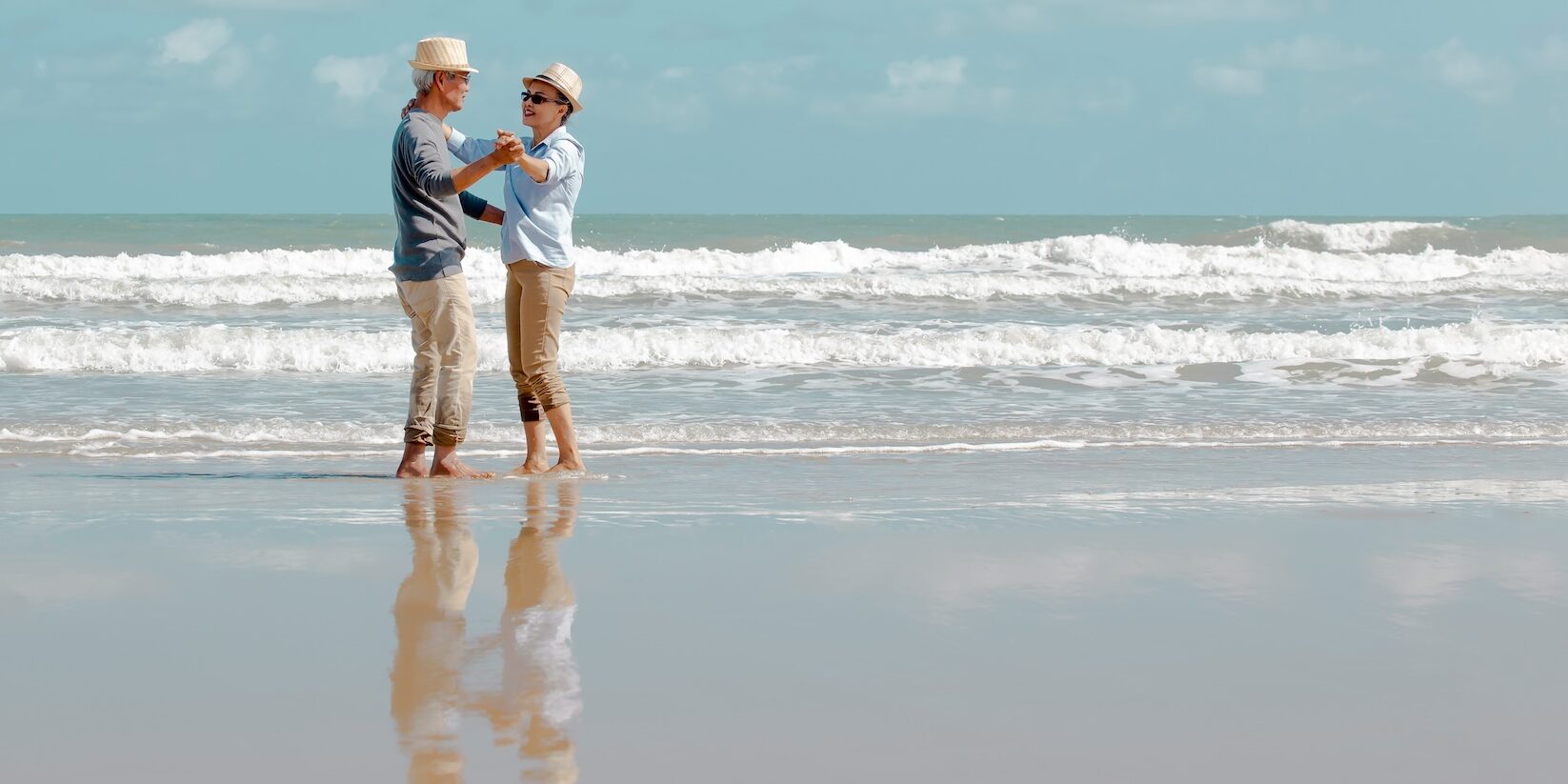 Happy  asian senior couple  dancing  on beach with blue sky background , Retirment travel  holiday healthy lifestyle Concept,Banner for text